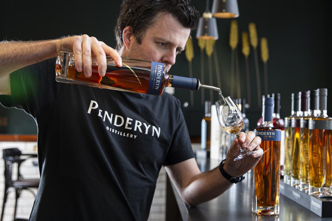 A worker pouring Penderyn whisky into a glass
