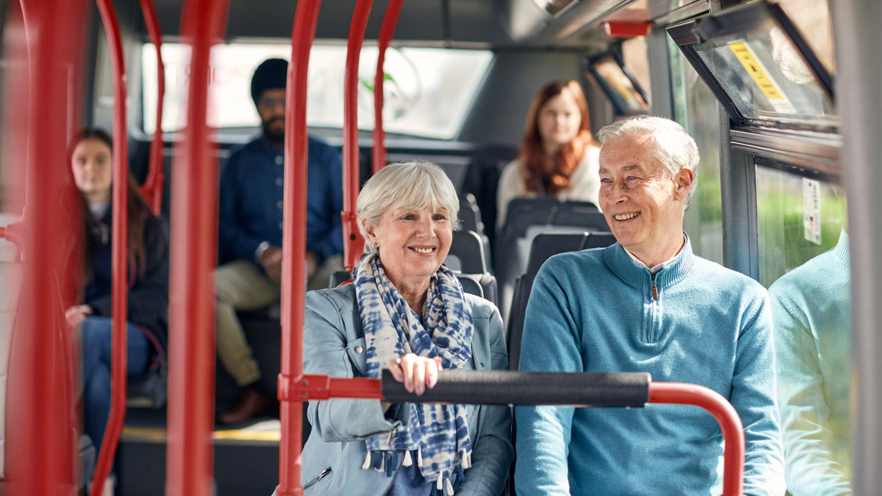 Two people sat smiling on a bus