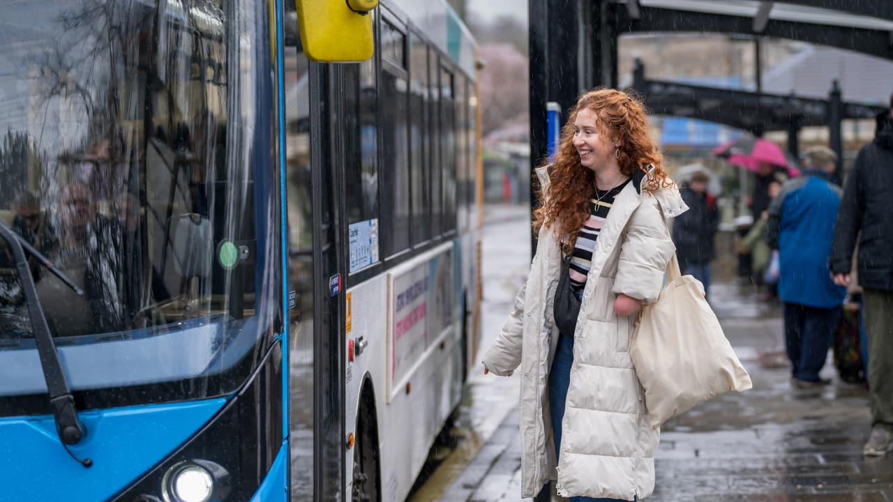 Woman about to board a bus in the rain