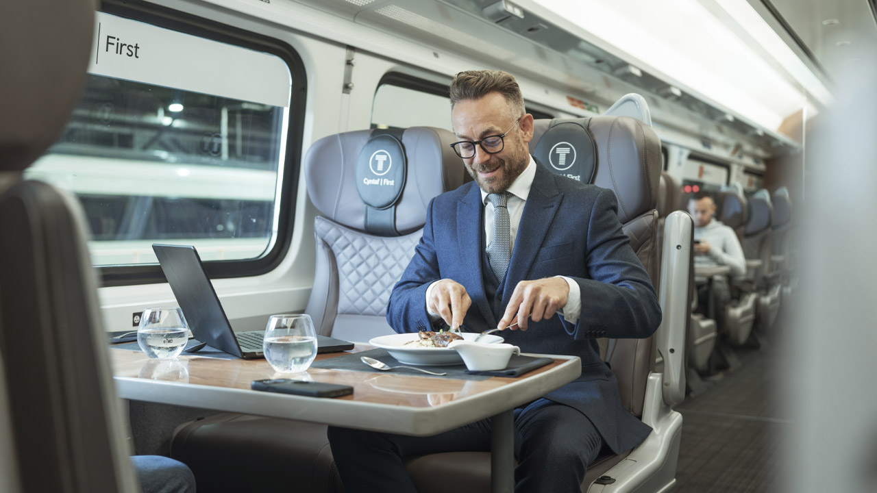 A well dressed man eating a First Class meal on a TfW train