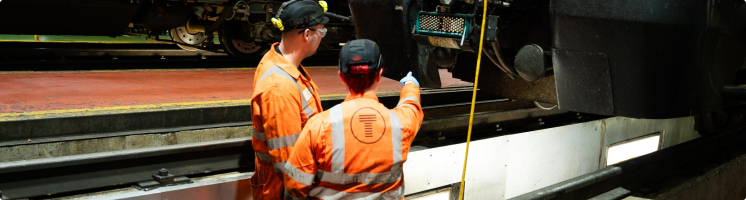 Transport for Wales workers inspecting underneath a train 
